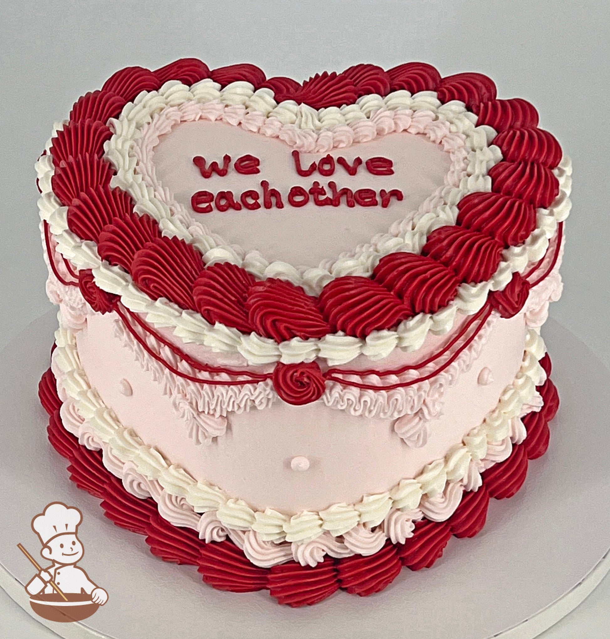 Heart Shaped cake with light-pink smooth icing, decorated with vintage style buttercream piping's in white, red and light-pink colors.