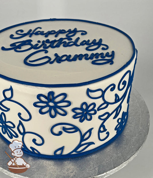 Single tier cake with white icing, and decorated with blue buttercream scrolls.