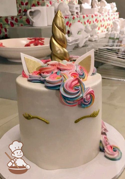 Cake decorated with a gold fondant horn and fondant ears. The cake also has colorful buttercream rosette swirls to look like a unicorn mane.