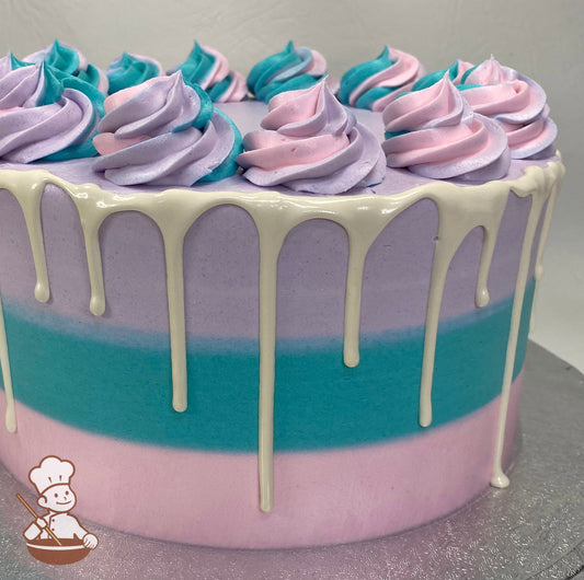 Single tier cake with pink, teal and purple icing and decorated with swirls on top of the cake and a white drip.