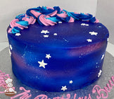 Cake decorated with colored icing to look like a galaxy, multi-colored buttercream swirls on top of the cake with some white fondant stars.
