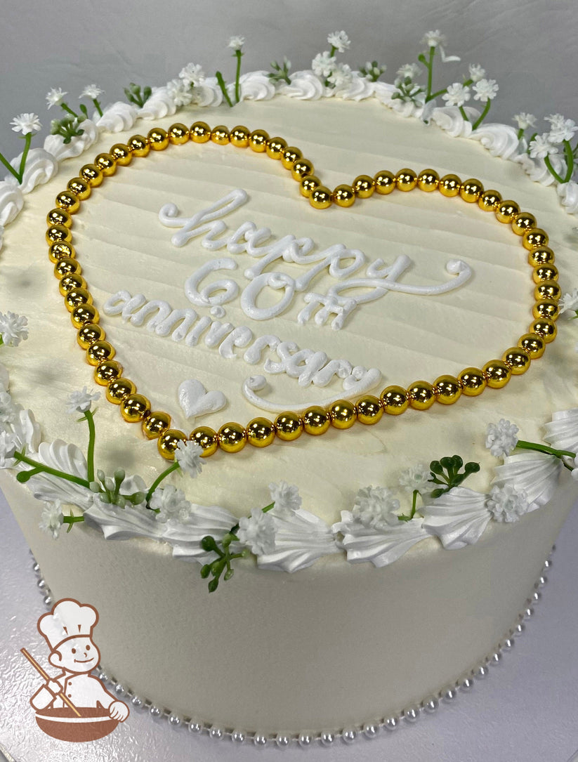 Cake with ivory icing and decorated with white pearls, baby's breath and gold pearls shaped into a heart with an anniversary message.