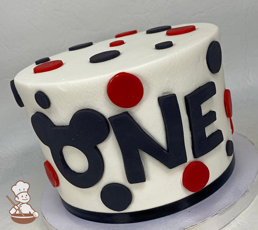 Single tier cake with smooth white icing and decorated with fondant black and red dots and a fondant ONE message in the front of the cake.