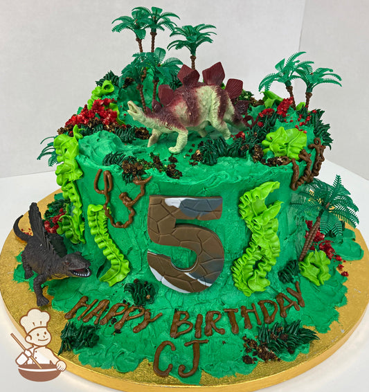 Single tier cake with green icing and decorated with ptoy dinosaurs and buttercream decoration for theme.