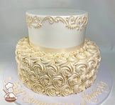 2-tier round cake with buttercream rosettes, has scrolls on cake wall at the top of the tier with an ivory ribbon on the base of the top tier.