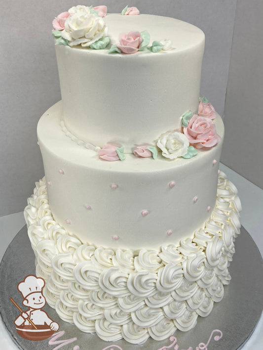 3-tier round cake with white buttercream rosettes on the bottom tier, light pink dots in the middle tier and pink and white roses on top.