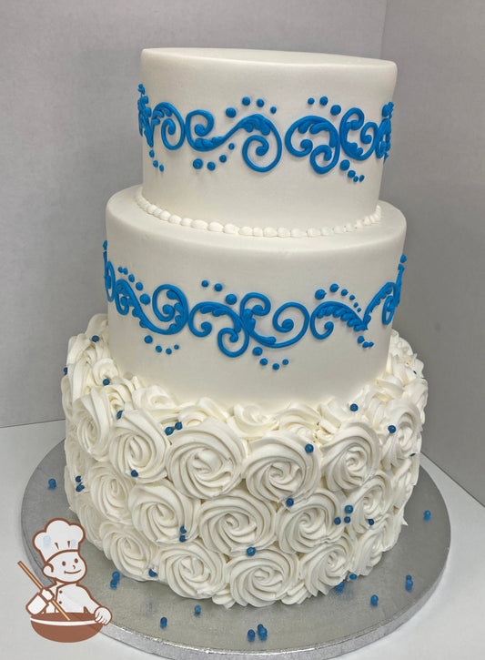 3-tier round cake with white buttercream rosettes on the bottom tier and white icing on middle and top tier with blue scrolls.