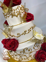 3-tier round cake with smooth white icing on all the tiers and decorated with metallic gold scrolls, gold butterflies and silk red roses.