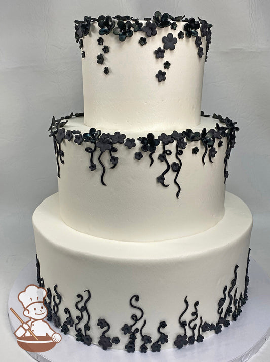 3-tier cake with smooth white icing and black small sugar flowers and buttercream black vines.