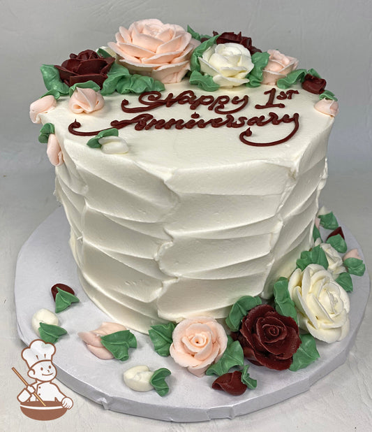 Cake with white textured icing and burgundy, light pink & white buttercream roses along with green leaves along top of cake & same on cakeboard.