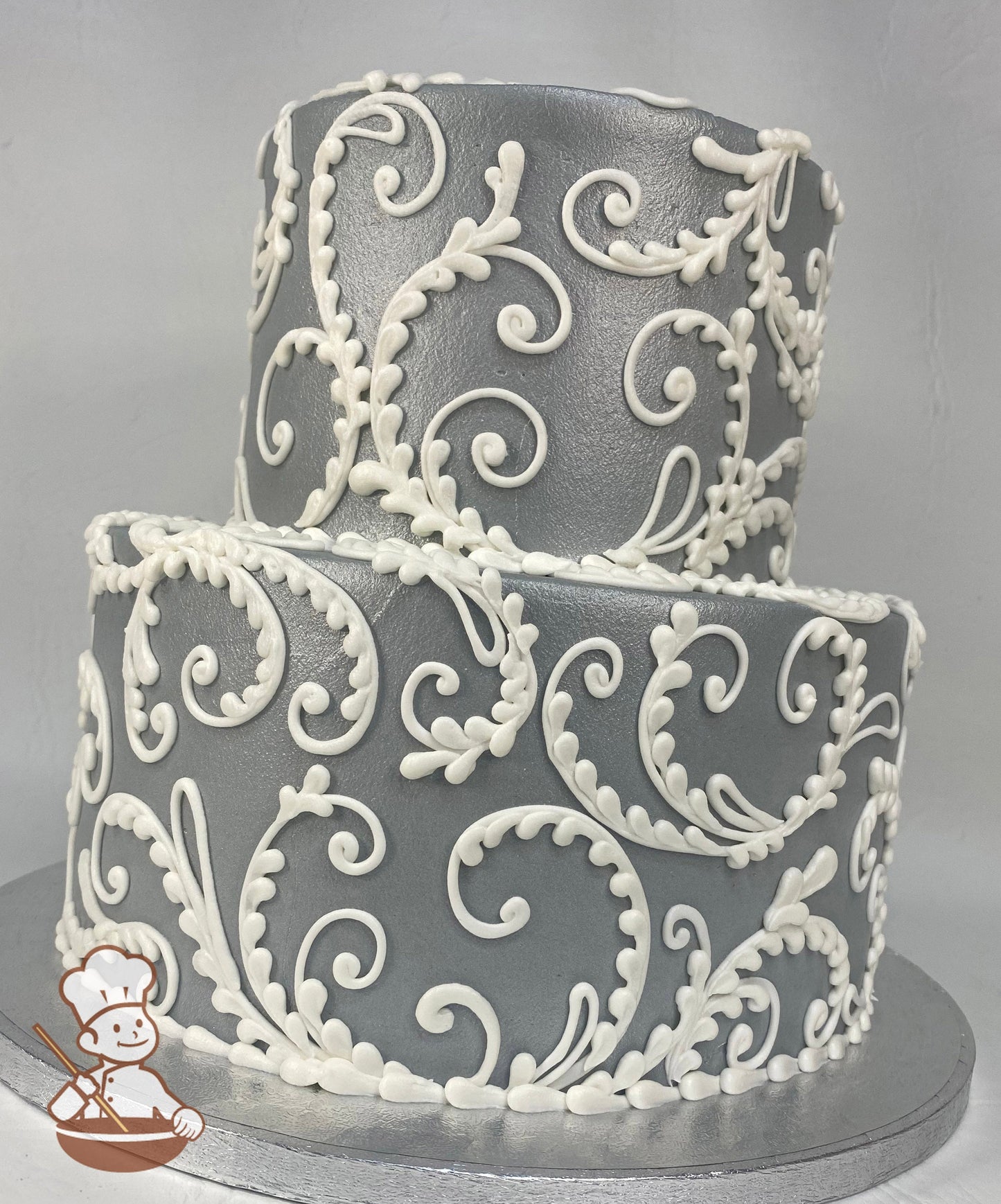2-tier round cake with gray icing and added shimmer to the cake and white buttercream scrolls all over the cake.