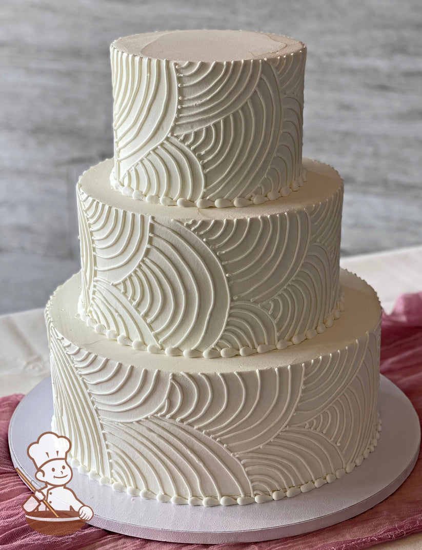 3-tier round cake with smooth white icing and hand-piped white buttercream curved lines all over cake walls. The cake has white beaded trims.