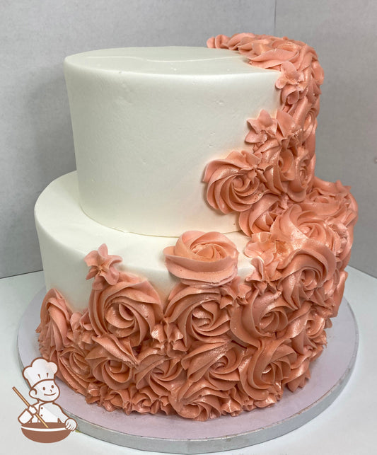 2-tier round cake with white icing and coral-colored buttercream rosettes cascading on the cake walls.