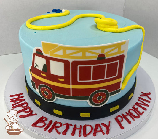 Round cake with light blue icing and printed fondant fire truck on cake wall. Cake also has a piped buttercream water-hose and road.