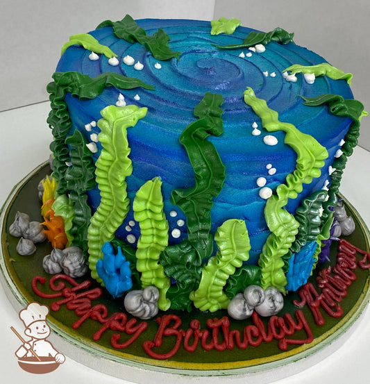 Single tier cake with textured icing to look like blue waves and hand-piped green seaweed, multi color coral and marbled-like rocks. 