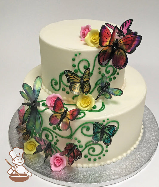 2-tier cake with smooth white icing and multi color plastic butterflies, yellow and pink sugar roses and green buttercream vine scrolls.