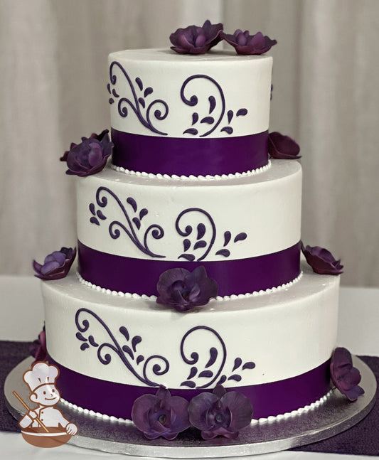 3-tier cake with white icing, decorated with purple sugar orchids, purple buttercream scrolls and a purple satin ribbon around each base.