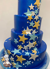 4-tier cake with white smooth icing which has been airbrushed a blue color and has light blue, white and yellow stars cascading on the tiers.