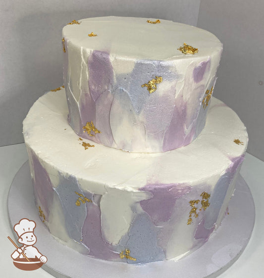 2-tier round cake with white icing, decorated with a palette knife texture in lavender colors, an added shimmer all over the cake and gold flake.