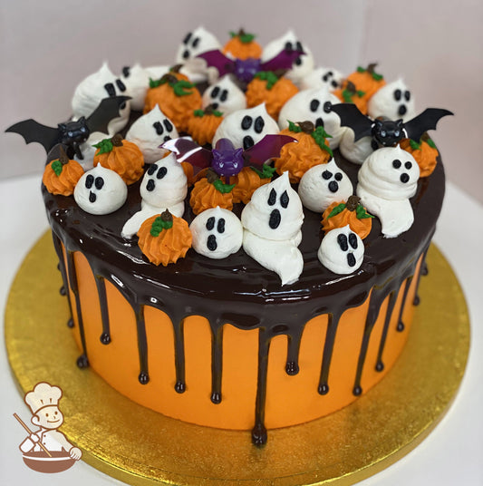 Single tier round cake with smooth orange icing and decorated with a chocolate drip and buttercream white ghosts and orange pumpkins.