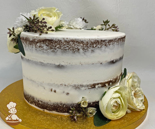Single tier cake with white icing decorated with a scraped texture to show some of the cake and silk flowers in cream and white colors.