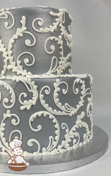 2-tier cake with grey smooth buttercream icing and hand-piped scrolls in white buttercream.