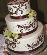 3-tier cake with smooth white icing and decorated with brown buttercream scrolls and a brown satin ribbon.