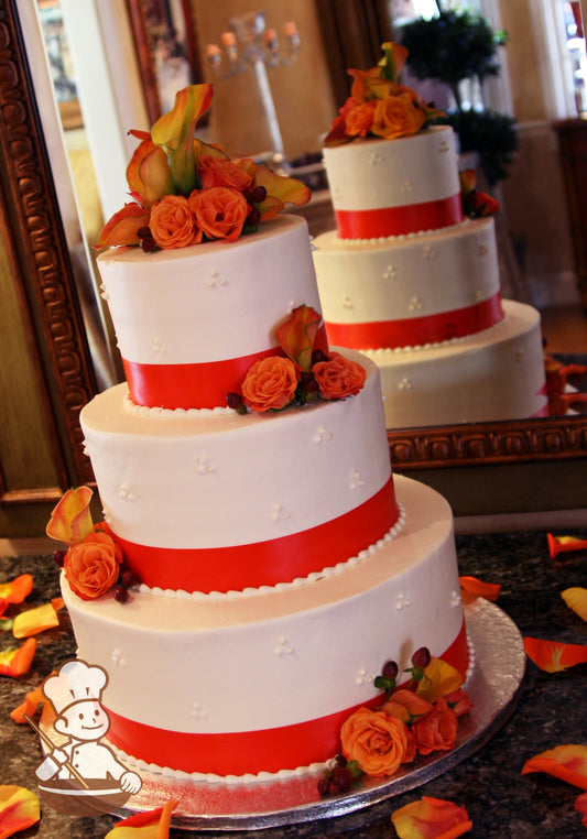 3-tier cake with smooth white icing and decorated with white buttercream tridot piping's and an orange satin ribbon on the base of each tier.