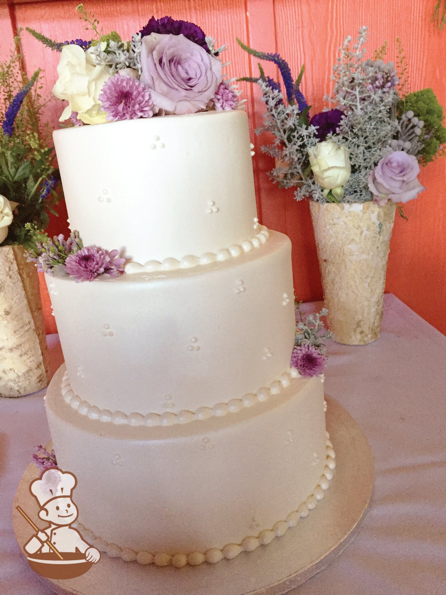 3-tier cake with smooth white icing and decorated with white buttercream tridot piping's and fresh flowers.