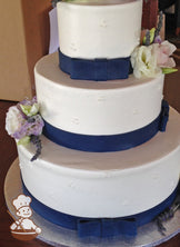 3-tier cake with smooth white icing and decorated with white buttercream tridot piping's and a navy blue fondant bow and band.