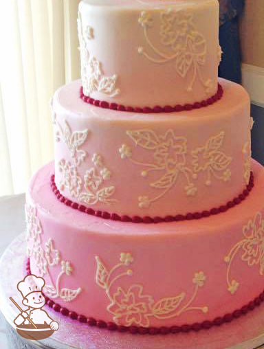 3-tier white cake with smooth icing and decorated with hand-piped white buttercream flowers and is sprayed a red color ombre.