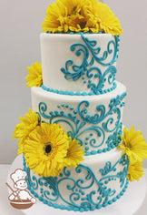 3-tier cake with smooth white icing and decorated with turquoise buttercream scrolls adn turquoise buttercream bead trims and yellow sunflowers.