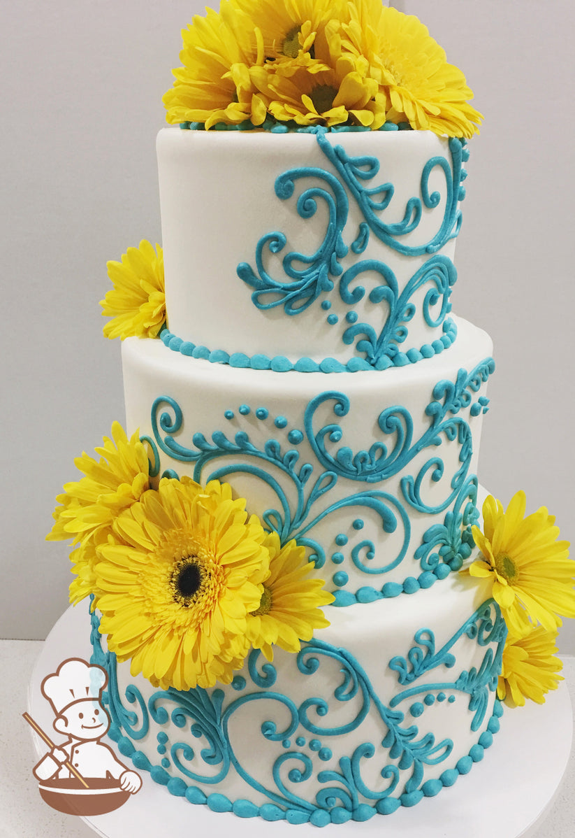 3-tier cake with smooth white icing and decorated with turquoise buttercream scrolls adn turquoise buttercream bead trims and yellow sunflowers.