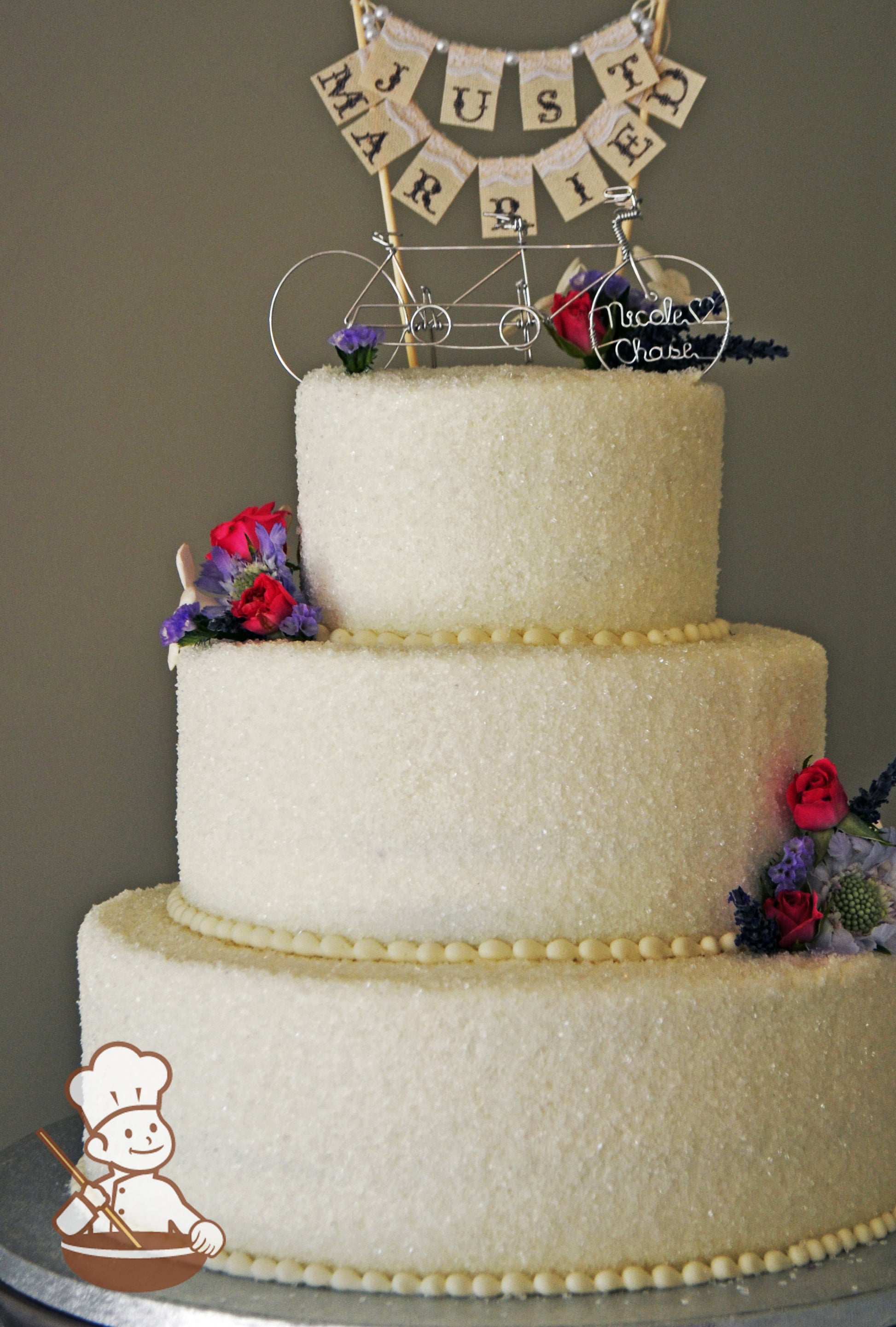3 tier round buttercream icing covered with sugar crystal and finished with bicycle just married bunting topper.