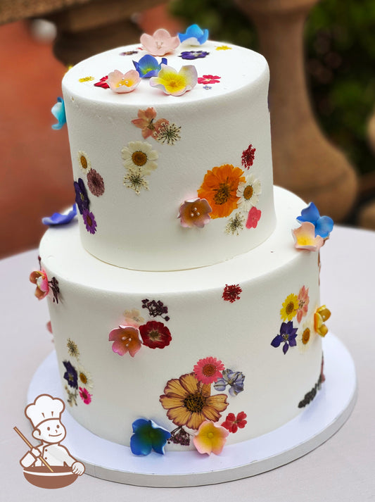 2 tier round buttercream wedding cake decorated with multi colored dried pressed flowers and sugar flower accents.