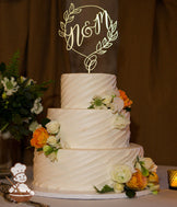 3-tier cake with white icing and decorated with a diagonal angle texture and white and orange fresh flowers.