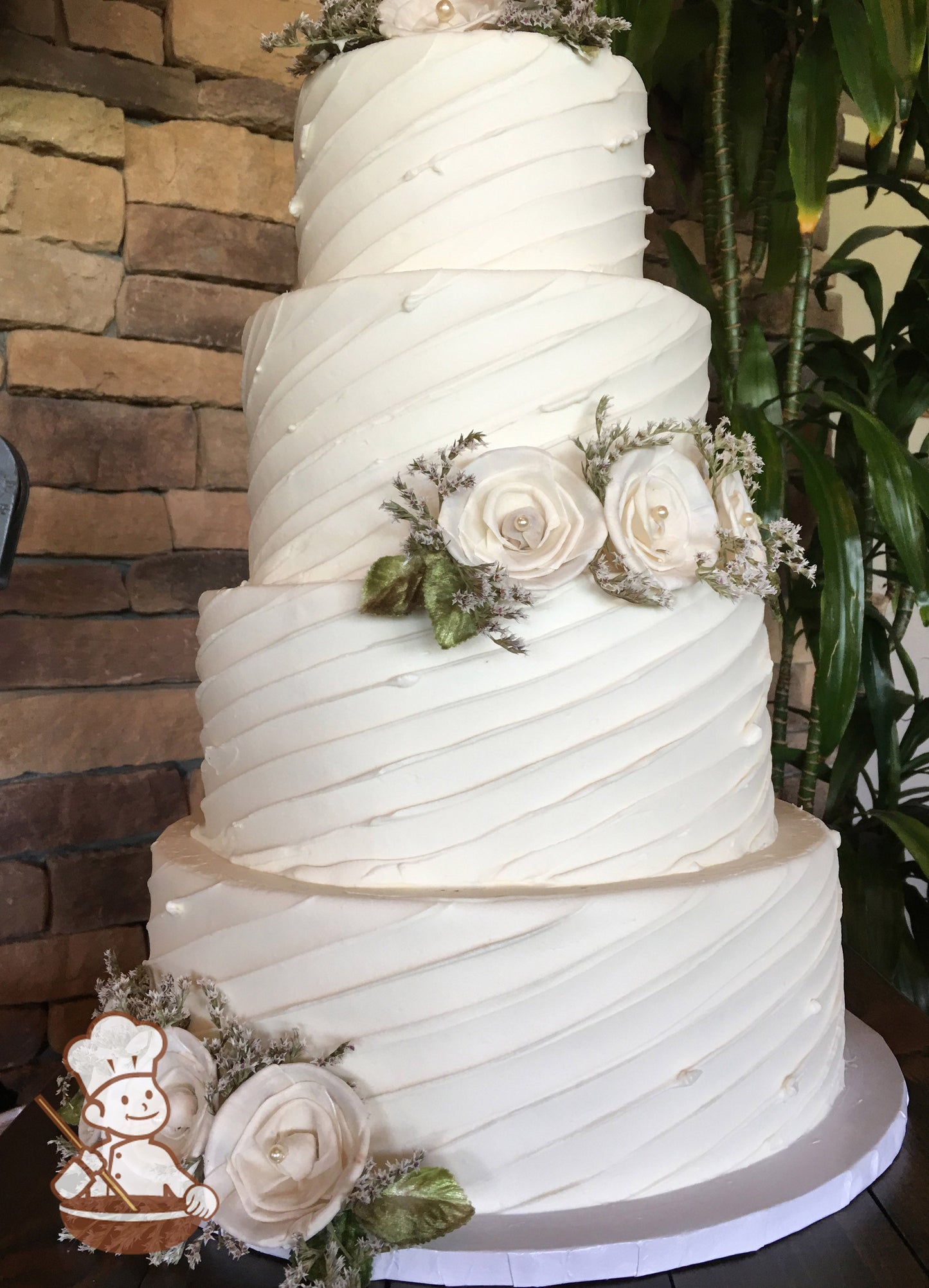 4-tier cake with white icing and decorated with a diagonal angle texture and white flowers.