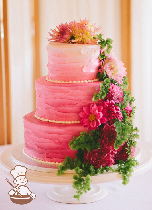 Cake with white icing decorated with a vertical texture and an added ombre airbrushed spray coloring from hot pink at bottom to white on top.