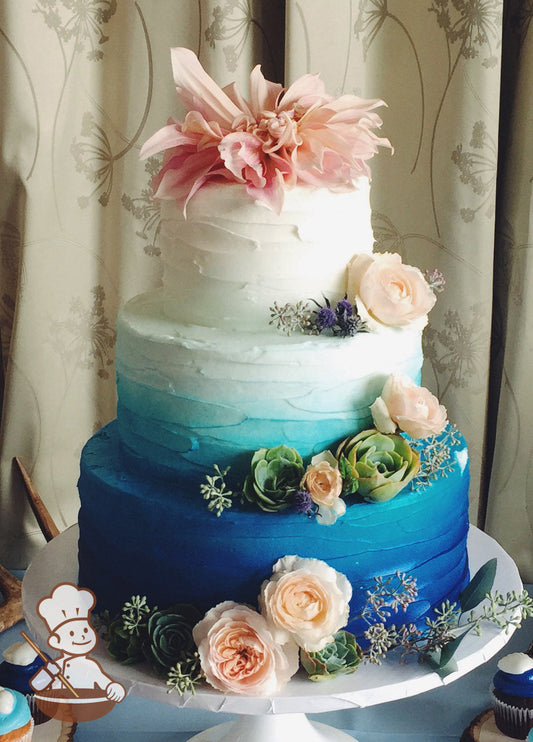 Cake with white icing and decorated with a messy horizontal texture and an airbrushed ombre coloring with dark-blue at bottom and white on top.