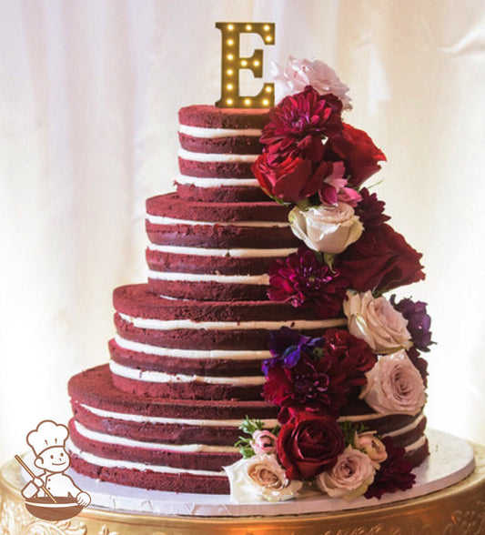 4-tier cake with no icing showing the inside cake layers and fillings with the cake being a red color red velvet cake.