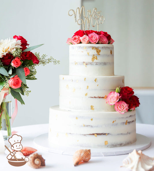 3-tier cake with white icing decorated with a scraped texture to show some of the inside of the cake and gold foil flakes.