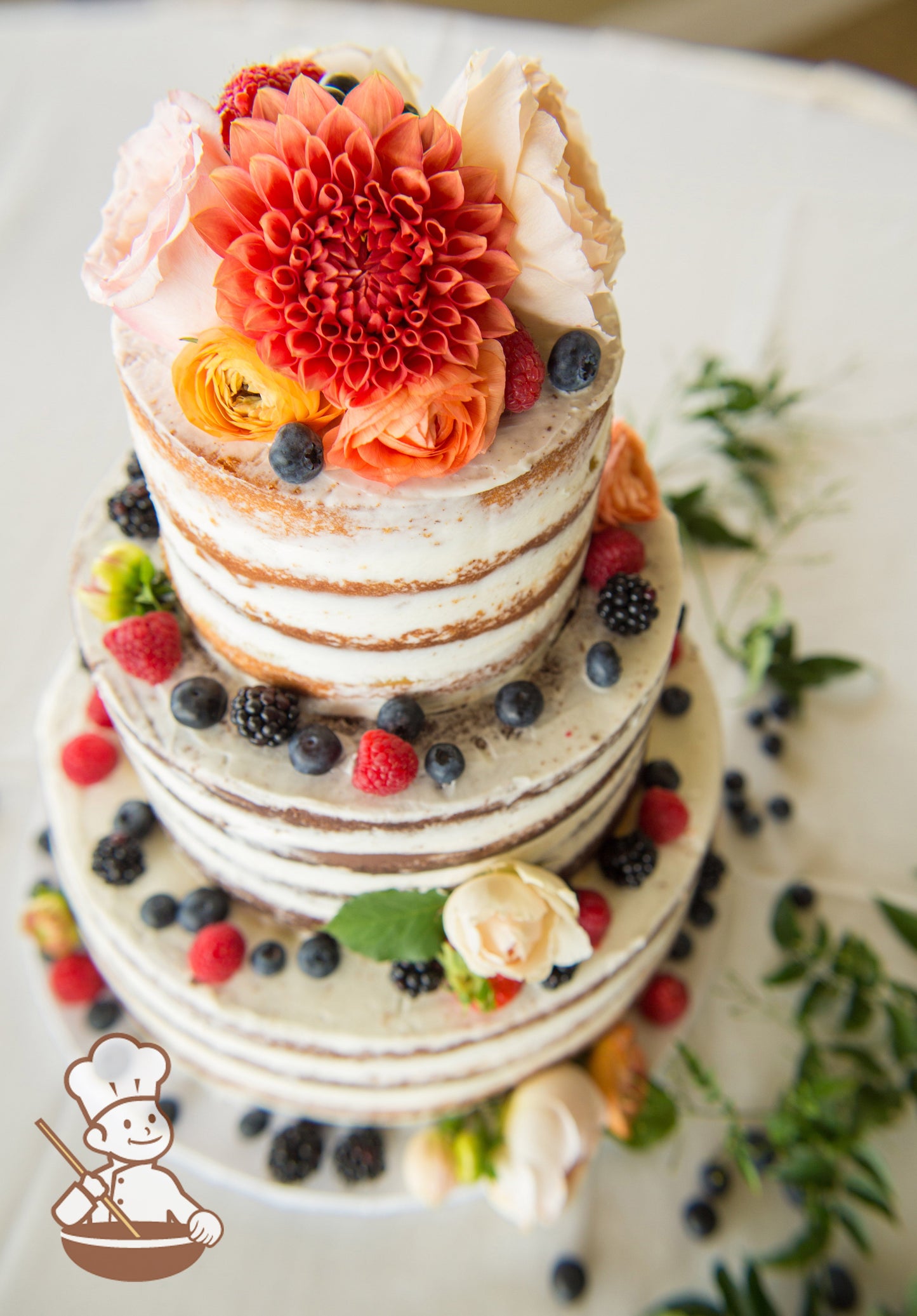 3-tier cake with white icing and decorated with a scraped texture to show some of the cake and fresh blackberries, blueberries and raspberries.