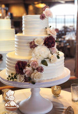 3-tier cake with white icing and decorated with a light horizontal texture and fresh flowers placed in a cascade pattern on the cake.