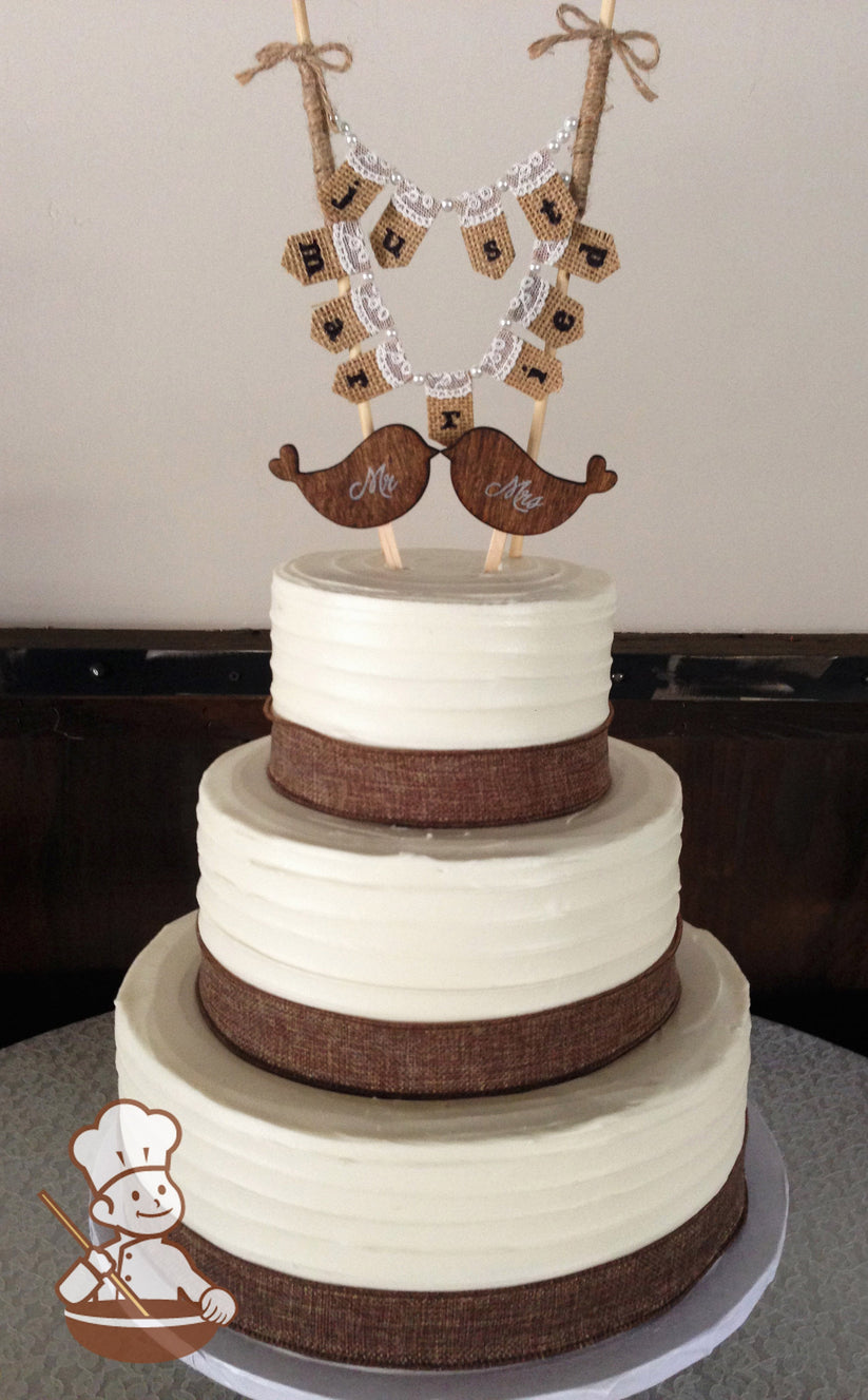 3-tier cake with white icing and decorated with a horizontal texture and a burlap ribbon on the base of each tier.