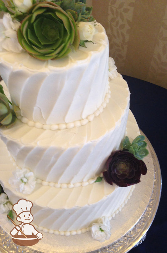 3-tier cake with white icing and decorated with an angled line texture and succulents.
