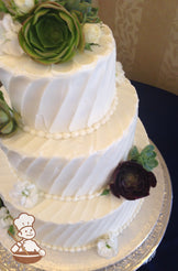 3-tier cake with white icing and decorated with an angled line texture and succulents.