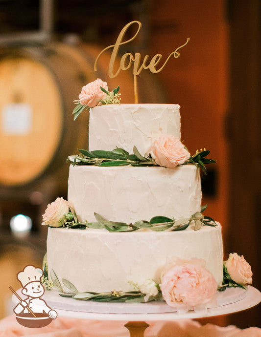 3-tier cake with white icing and decorated with a light stucco-like texture and fresh flowers and vines.