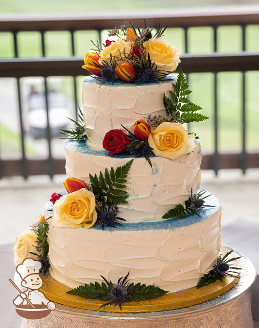 3-tier cake with white icing and decorated with textured icing and blue sanding sugar.
