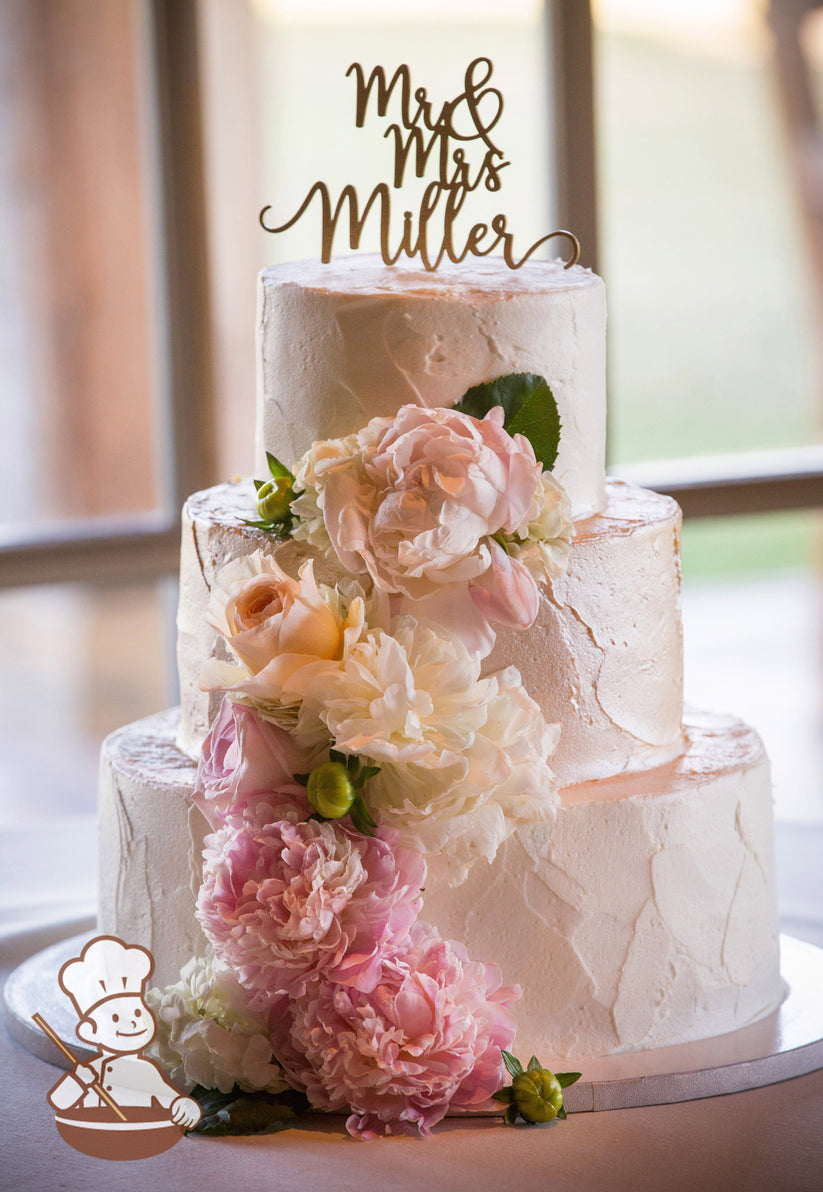 3-tier cake with white icing and decorated with a light texture and added shimmer spray.