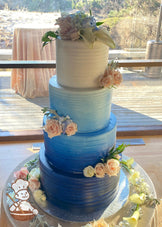 Cake with white icing decorated with a light horizontal texture and an airbrushed ombre coloring starting with dark-blue at bottom to white.